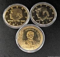 Top side of three gold plated Donald Trump tokens showing front profiles and inscriptions with years 2018 and 2019