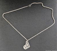Front view of the metal necklace with oval-link chain and West Coast Native style pendant displaying animal motif design.