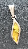 Close-up of the amber pendant showing the marquise-shaped polished amber with golden inclusions set in polished sterling silver.