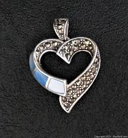 Solid sterling silver heart-shaped pendant with marcasite and opalescent inlays on a black background