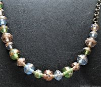 Close-up of multicolored Murano glass style beads showing detailed floral and speckled patterns with gold-tone chain.