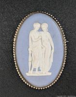 Close-up front view of the vintage silver Wedgwood brooch showing the detailed cameo of two classical figures on a blue background with beaded silver edge.