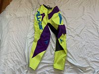 Pants laid flat showing front view with detailed color blocking and branding.