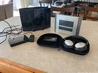 Photo showing GE UltraPro Optima TV antenna, LaCrosse Technology radio controlled clock, Bose noise cancelling headphones in case, and Tenda 8 port Gigabit Ethernet switch on a kitchen table.