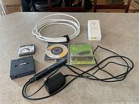 Photo of the full lot showing Netgear Powerline adapter, Noosy SIM cutter, TP-Link switch, Timetec RAM in packaging, CD lens cleaner, J5 Create USB hub, and white Ethernet cord coiled.