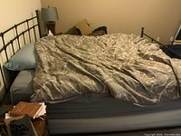 Full view of king sized bed with metal frame and mattress, comforter and bedding present but not included