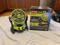 Photo shows Ryobi One+ bucket top misting fan with transparent misting tube and original packaging.