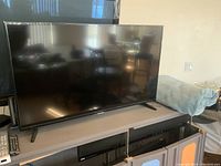 Samsung flat screen TV on beige table with remote control beside it.