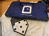 Blue Swingaway carry bag with logo and contact info, along with the heavy black base featuring a metal plate with bolt holes.