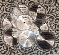 Full layout of the eight 10-inch Mastercraft carbide-tipped saw blades arranged flat on a patterned carpet, showing branding, labeling and protective rims.
