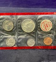 Front side of one 1969 Mint Set showing coins including the half dollar, quarter, dime, nickel, and penny in sealed plastic packaging with red borders and 'Property of the Mint' label