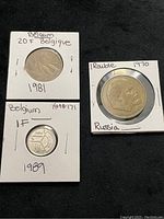Front view of three foreign coins mounted in cardboard holders: two Belgium coins from 1981 and 1989, and one Russian coin from 1970