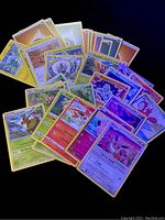 Photo of assorted Pokémon cards laid out in a fan arrangement showing a variety of Pokémon characters including Eevee, Vulpix, Chespin, and others.