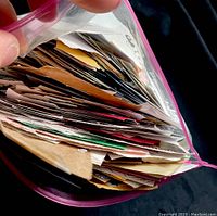 Side view of clear zipper plastic bag filled with assorted postage stamps attached to paper