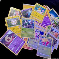 Top view of a pile of Pokémon trading cards showing various character cards including Rotom, Togedemaru, Wobbuffet, Skiddo and others.