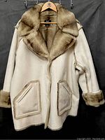 Front view of the women's fur coat showing beige outer fabric with brown fur collar, sleeve cuffs, and pocket trim.