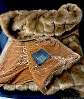 Brown fur throw folded showing plush fur exterior and soft velvet backing with Dennis Basso Home label.
