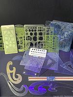 Various drafting stencils including circle templates, geometric shapes, and alphabet cutouts.