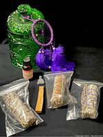 Full lot overview showing all ritual items including sage bundles, palo santo, green glass canister, purple dreamcatcher, oil bottle, and figurine.