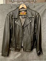 Front view of the black leather Harley Davidson women's coat showing stud detailing and zipper closure.