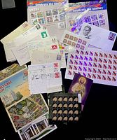 Photo of assorted postal cards, envelopes with stamps, and commemorative 'Celebrate the Century' stamp sheets from the 1920s and 1930s.