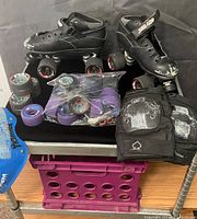 Photo showing the pair of worn women's roller derby skates, extra replacement wheels in various colors inside a plastic bag and loose, black knee pads with protective caps.