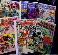Photo showing seven various comic books from Marvel and DC. Covers visible showing The Official Handbook of the Marvel Universe, The Avengers, Flash, and Excalibur.