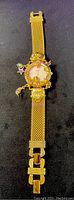 Full view of the vintage Kirks Folly Dreamtime 15th Anniversary women's watch with gold-tone metal mesh band laid flat showing overall design and attached charms.