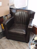 Front angle view of the brown leather armchair showing stitched backrest and cushioned seat.
