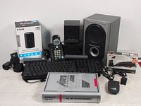 Wide view of all items showing router, keyboard, phone, speakers, and book