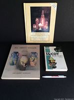 Photo showing all three reference books about Roseville, Weller, and McCoy Pottery with a pen for scale.