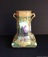 Front view of vase showing hand painted scenic mountain, trees, flowers and gilded morriage beaded border at top