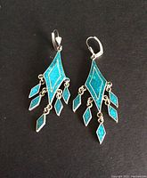 Pair of sterling silver earrings with turquoise inlay on black background.