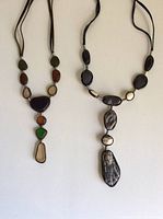 Two vintage necklaces on a white background. One necklace has multicolored beach glass pieces in leather, the other has black and cream marbled stones in leather.