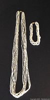 Photo showing full length of six strand seed pearl necklace and matching six strand seed pearl bracelet both with gold plated clasps.