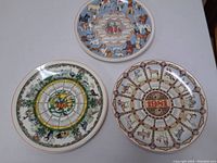 Three Wedgewood calendar plates for years 1980, 1981, and 1984 arranged in a triangular formation showing full calendar designs for each.