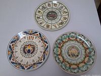 Three Wedgewood calendar plates from 1983, 1979, and 1878 shown together on flat surface
