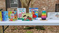 Table display with colorful children's sensory and educational books and a wooden stacking rings toy.