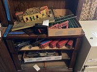 Overview of shelving unit showing station on top, transformer, fencing box, train cars on middle shelf and track box at bottom
