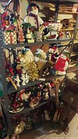 Wide view of metal shelves filled with assorted Christmas decorations including figures of Santa, snowmen, small trees, candles, and sleds