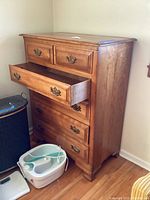Chest of drawers angled showing open middle drawer with dovetail joinery and brass handles.