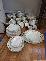 Full view of all dinnerware pieces arranged on floor, showing plates, cups, pitchers, and serving items
