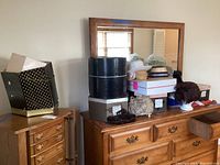Dresser top with assorted men's and women's hats, some wigs displayed on foam heads, stacked hat boxes.