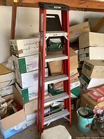 Full view of 6-foot Werner fiberglass step ladder standing upright surrounded by boxes.