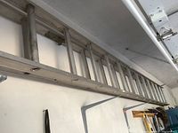 Side view of aluminum extension ladder mounted on wall showing full length, aluminum rails and rungs.
