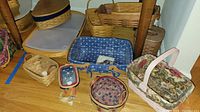 Photo of multiple Longaberger baskets of various sizes and fabric liners including a blue floral print and a basket with a pink floral liner and handle.