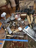 Overview of all kitchen utensils, graters, rolling pins, hand mixers, cookie cutters, and kitchen art print laid out on a carpeted floor.