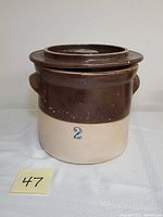 Front view of antique 2 gallon farmhouse crock with brown glaze upper half and natural stoneware lower half showing blue number '2'