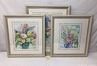 Group photo of three framed watercolor flower paintings showing colorful floral still life compositions in pastel and vibrant tones.