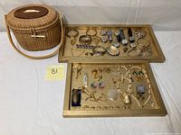 Photo showing the full lot including two trays with assorted watches and costume jewelry, and the Nantucket style woven basket to the side.